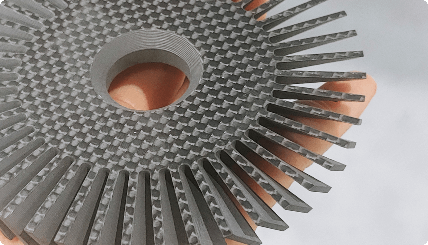 person holding a small precise part cut from carbon fiber